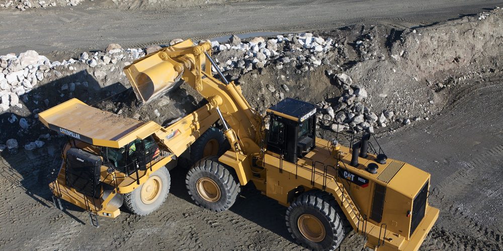 Overhead view of a catepillar contruction veihicle lifting rocks into a catepillar dump truck